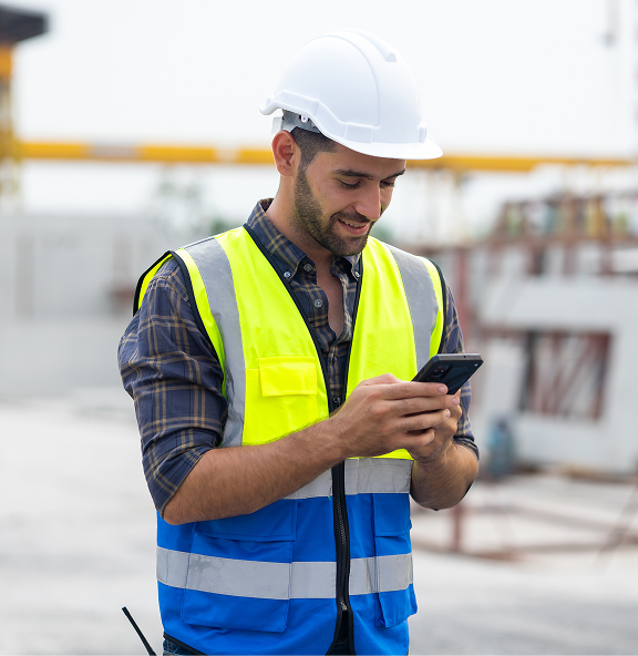 Field worker in a hard hat and high-visibility vest using WorkAware on a mobile phone