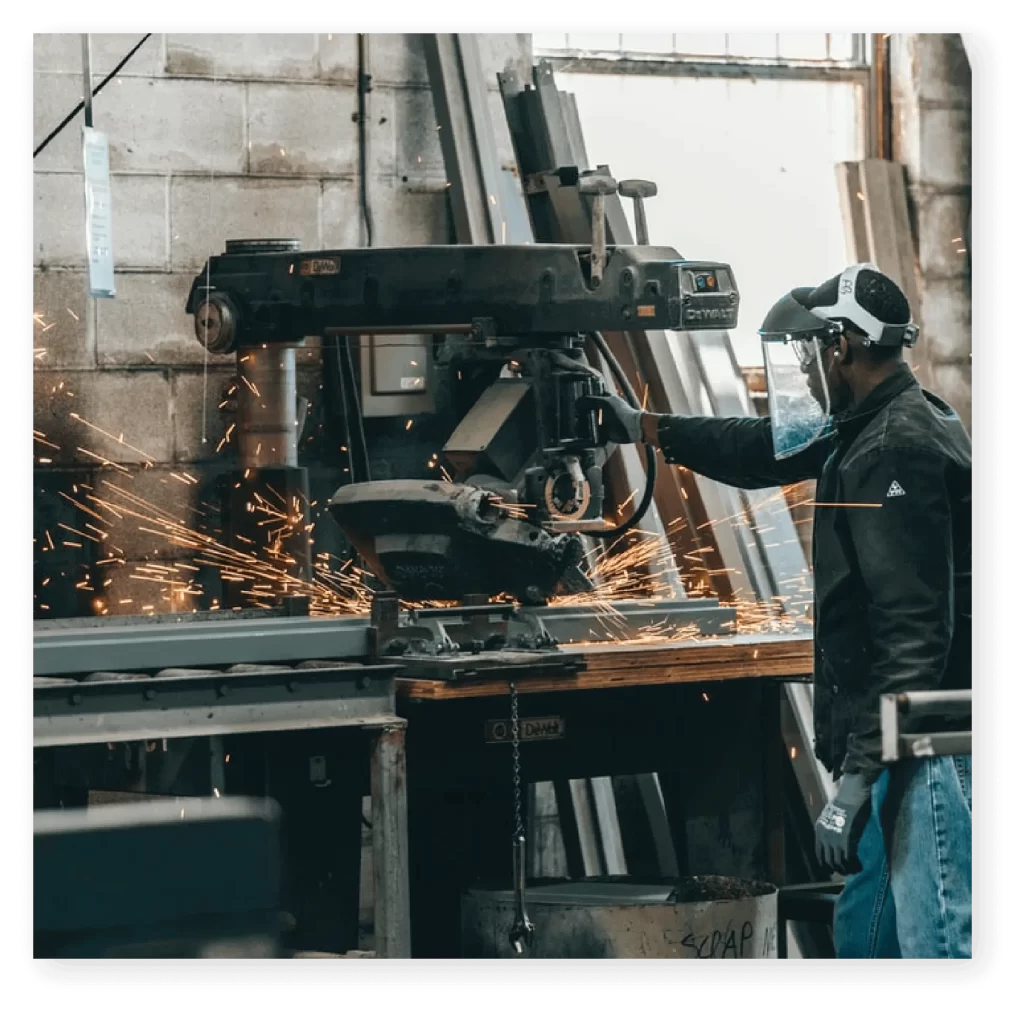 A man operating a steel cutting machine in a workshop