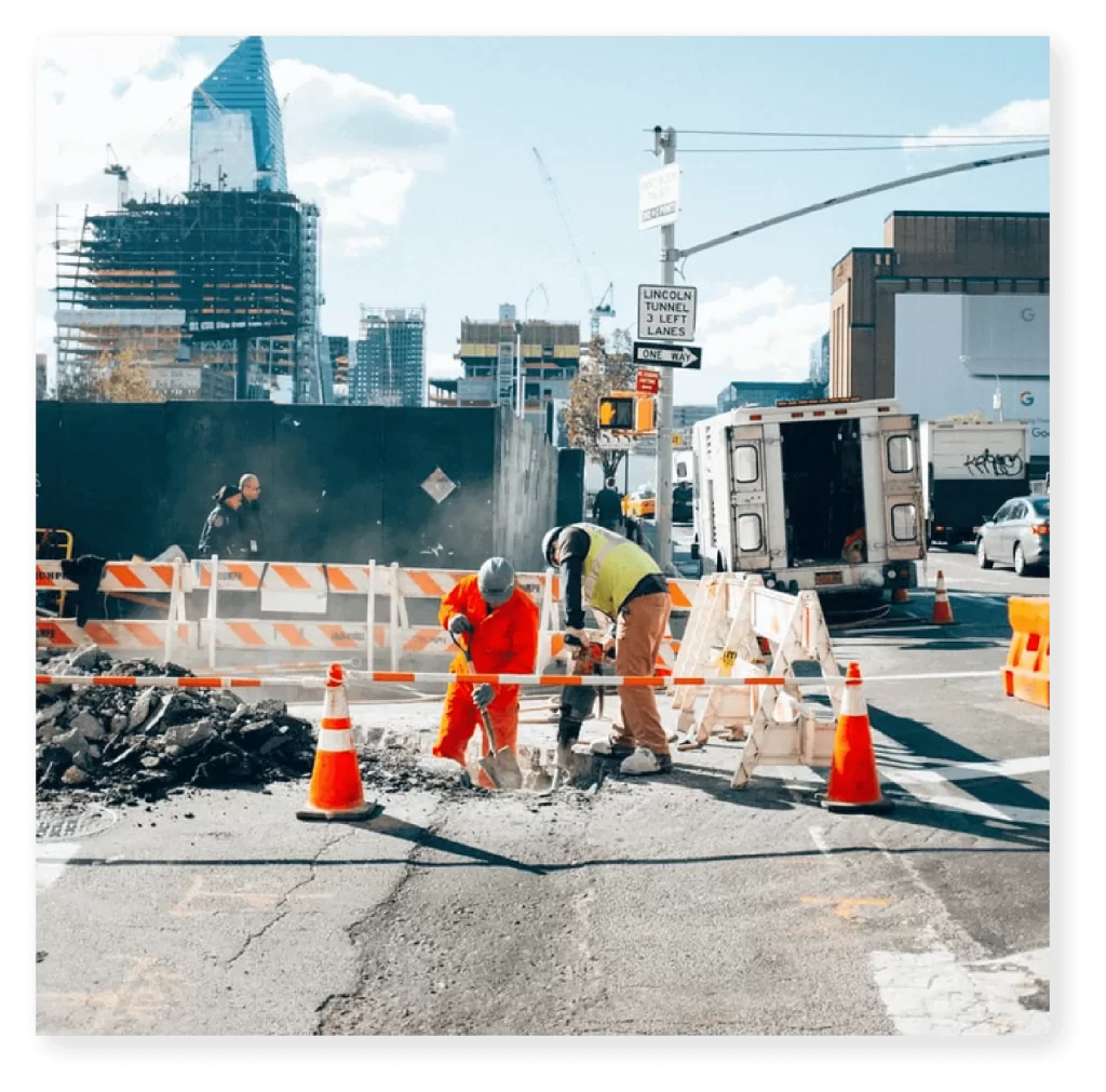 Workers operating a road drilling machine to cut through concrete